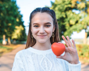 Happy teenage girl holds a fruit shaped like a heart