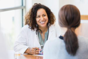 A smiling female doctor listens as a female patient discusses her health.