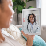 Woman holding iPad talking with her doctor over a telehealth visit.