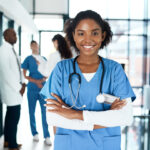 Portrait of a confident young doctor working in a hospital with her colleagues in the background